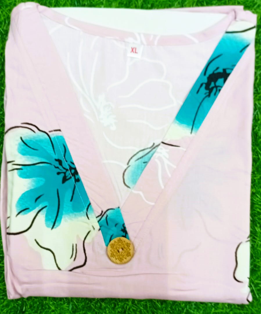 Folded pink garment with blue floral design on a green grass background