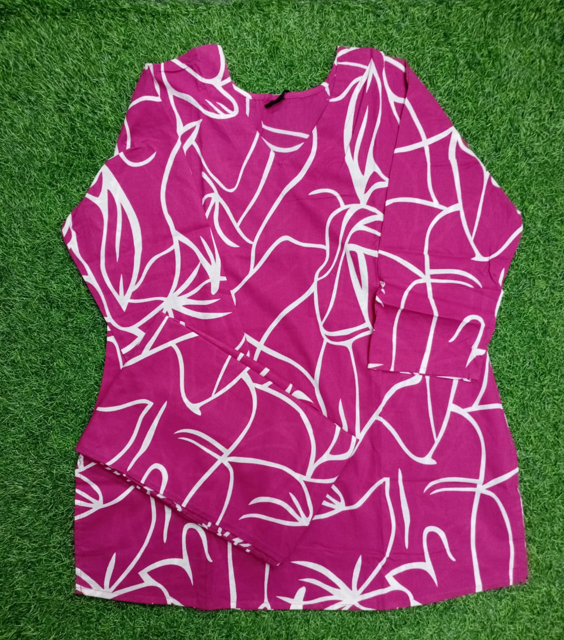 Pink dress with white floral pattern on a green grass background