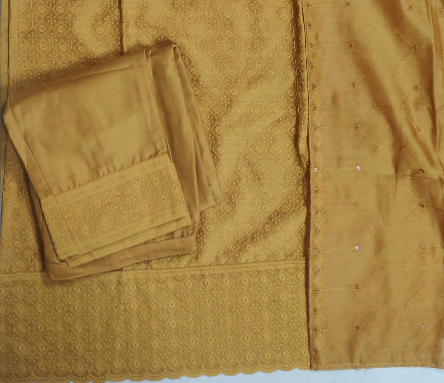 Gold fabric with intricate patterns and a folded piece of fabric on a matching background