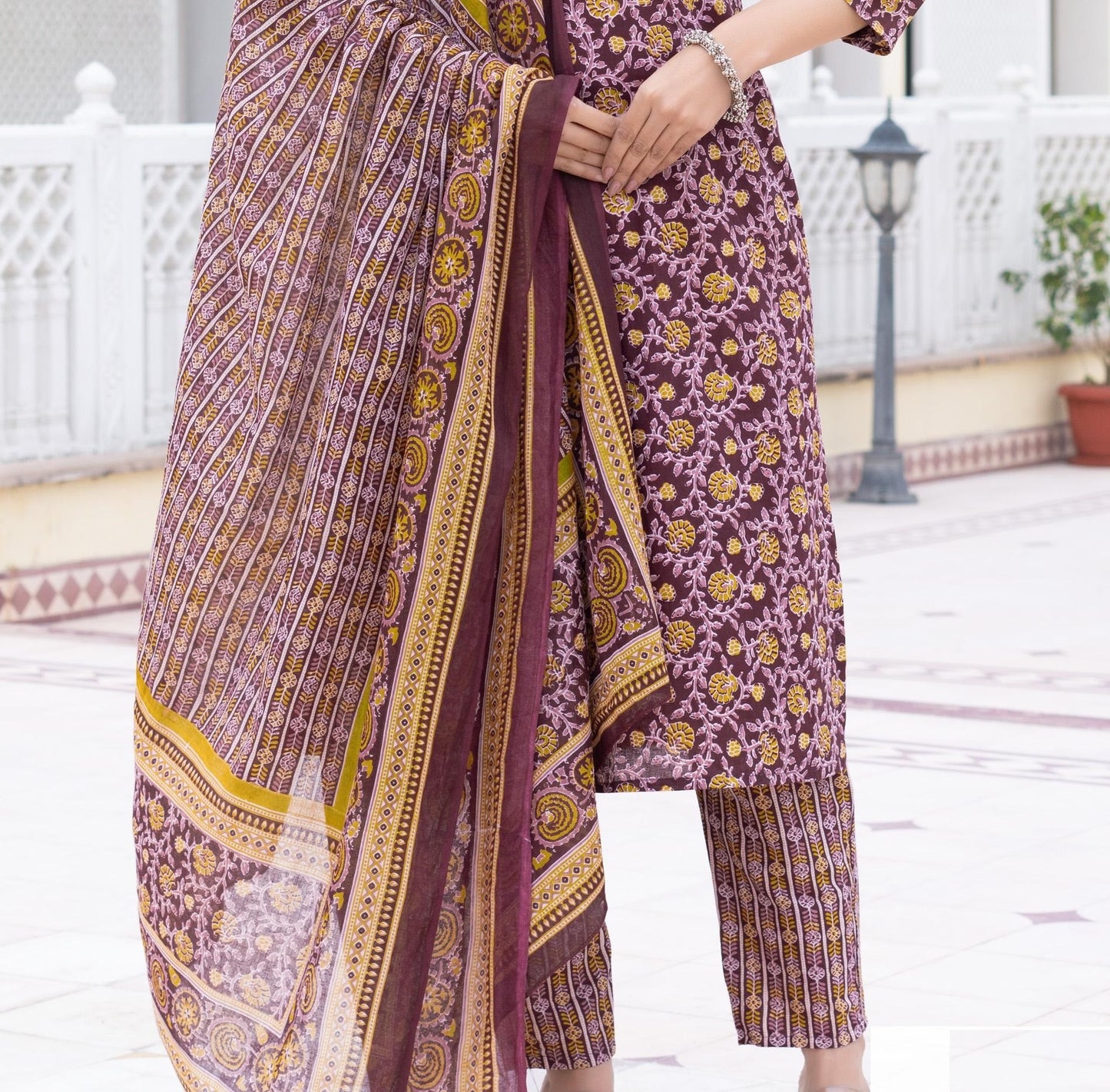 Purple and gold patterned outfit with a scarf in an outdoor setting