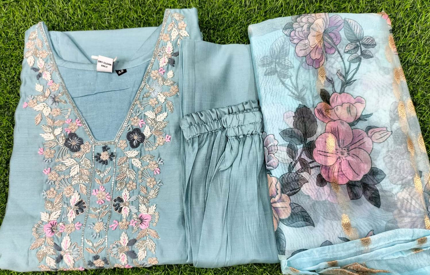 Light blue outfit with floral embroidery on a grass background