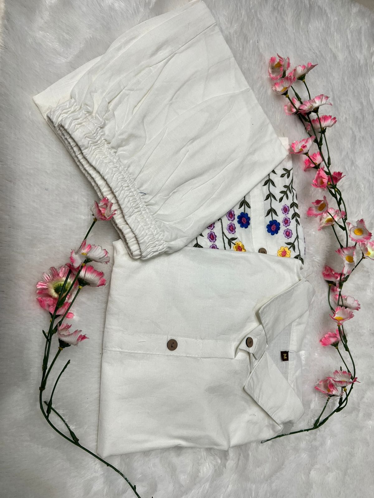 Two pieces of white clothing with floral patterns on a light gray background