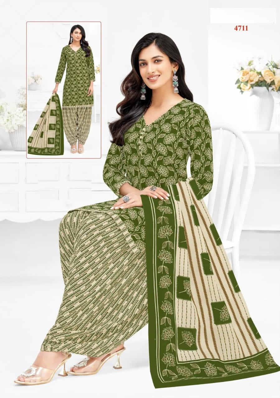 Woman wearing a green and beige traditional outfit with a matching dupatta, sitting on a white couch.