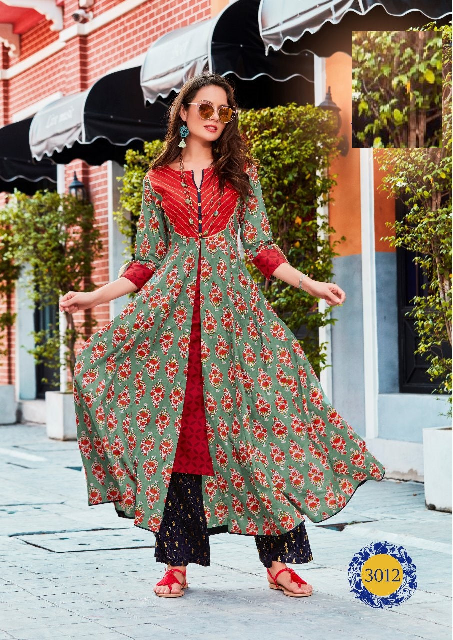 A woman wearing a long kurti with red and green colors and front buttons, paired with black pants and red shoes, standing on a street.