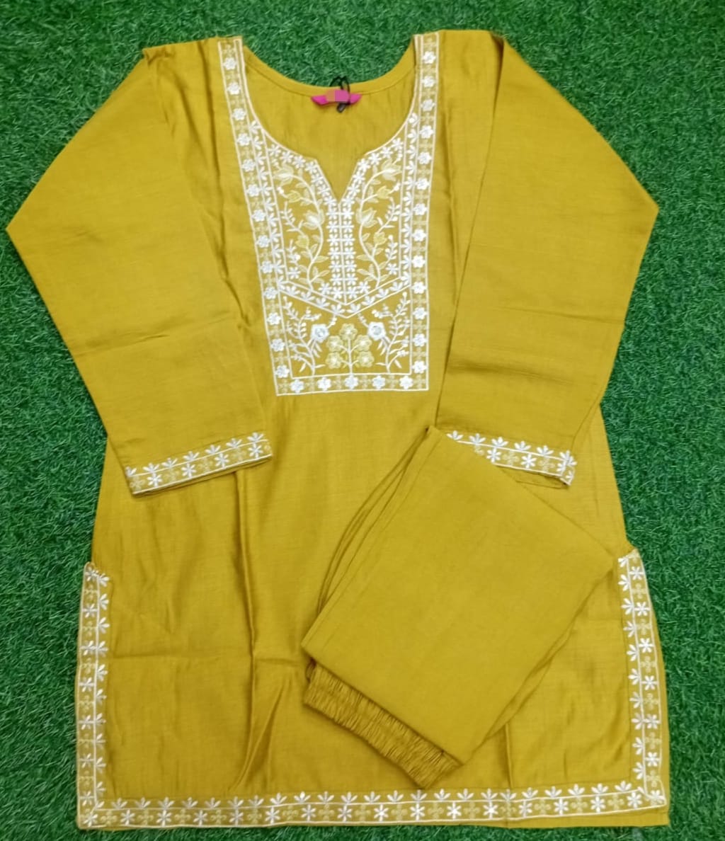 Mustard yellow traditional outfit with white embroidery on a green background