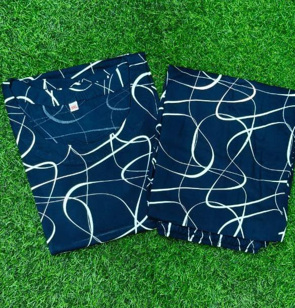 Two pairs of blue shorts with white abstract patterns on a green grass background
