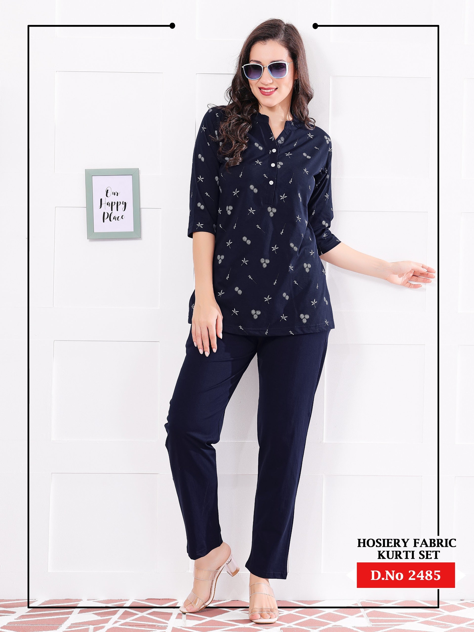 Woman wearing a navy blue kurta with white patterns and matching pants against a white wall.