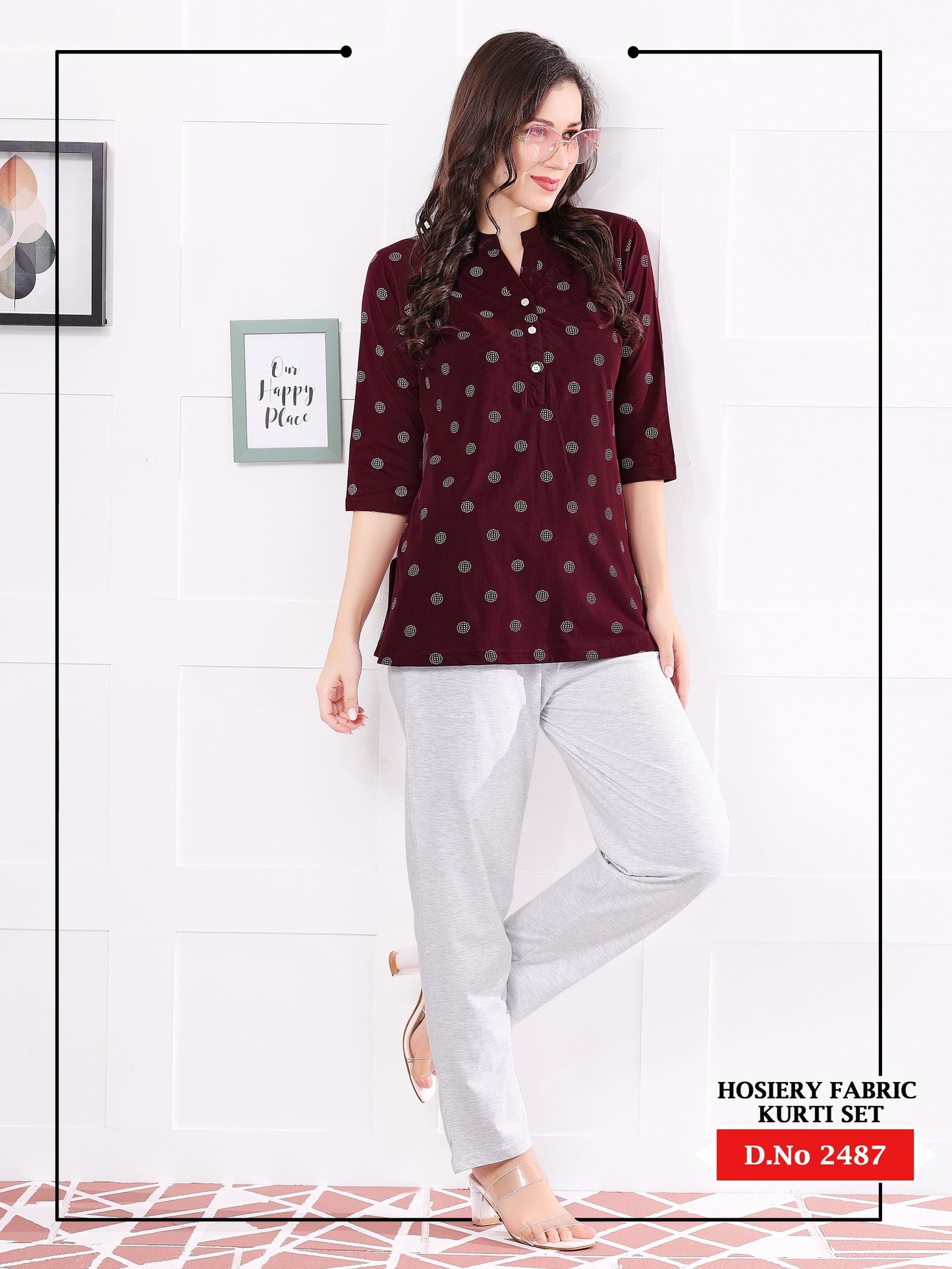 Woman wearing a maroon polka dot top and light gray pants on a white background