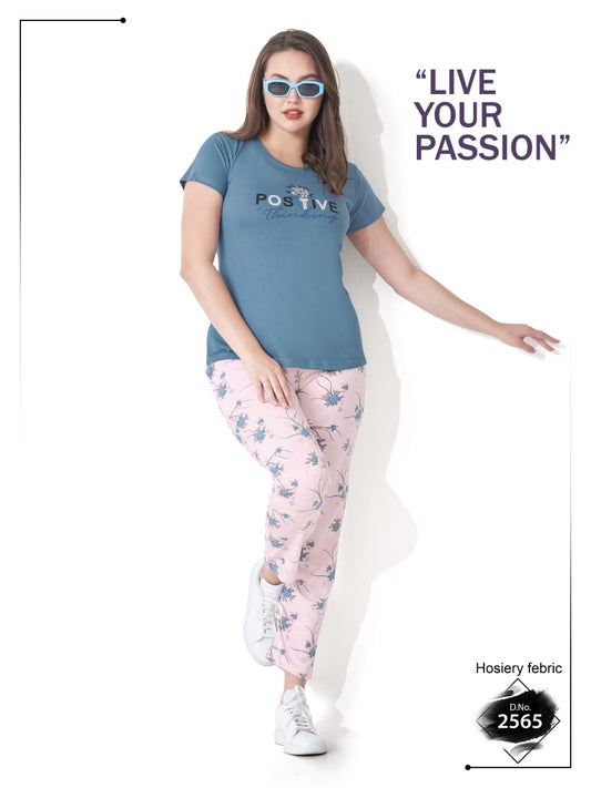 Woman wearing a blue t-shirt and pink floral pants with sunglasses, standing against a white background.