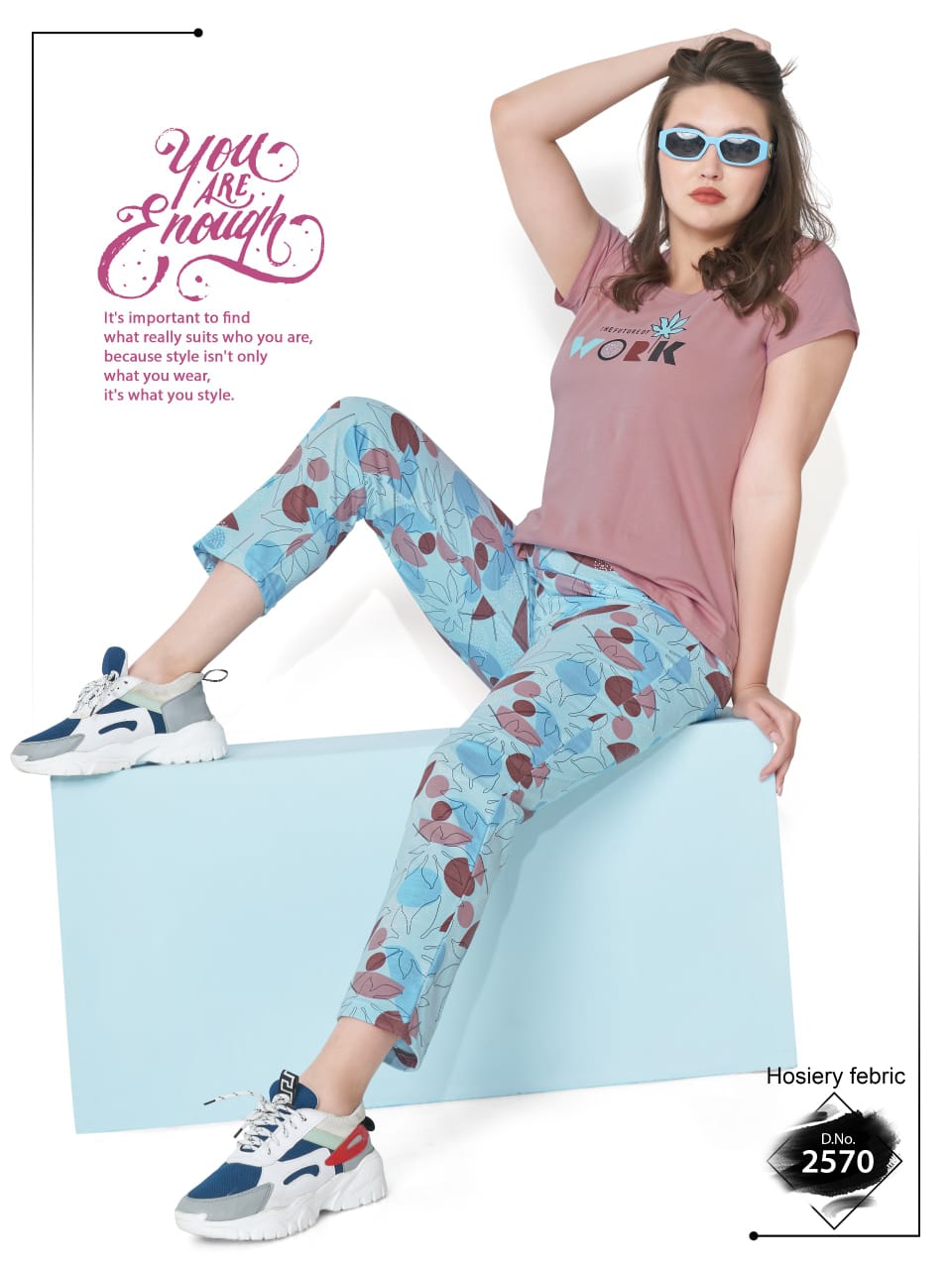 Woman wearing a pink t-shirt and patterned pants sitting on a light blue block with text and branding.