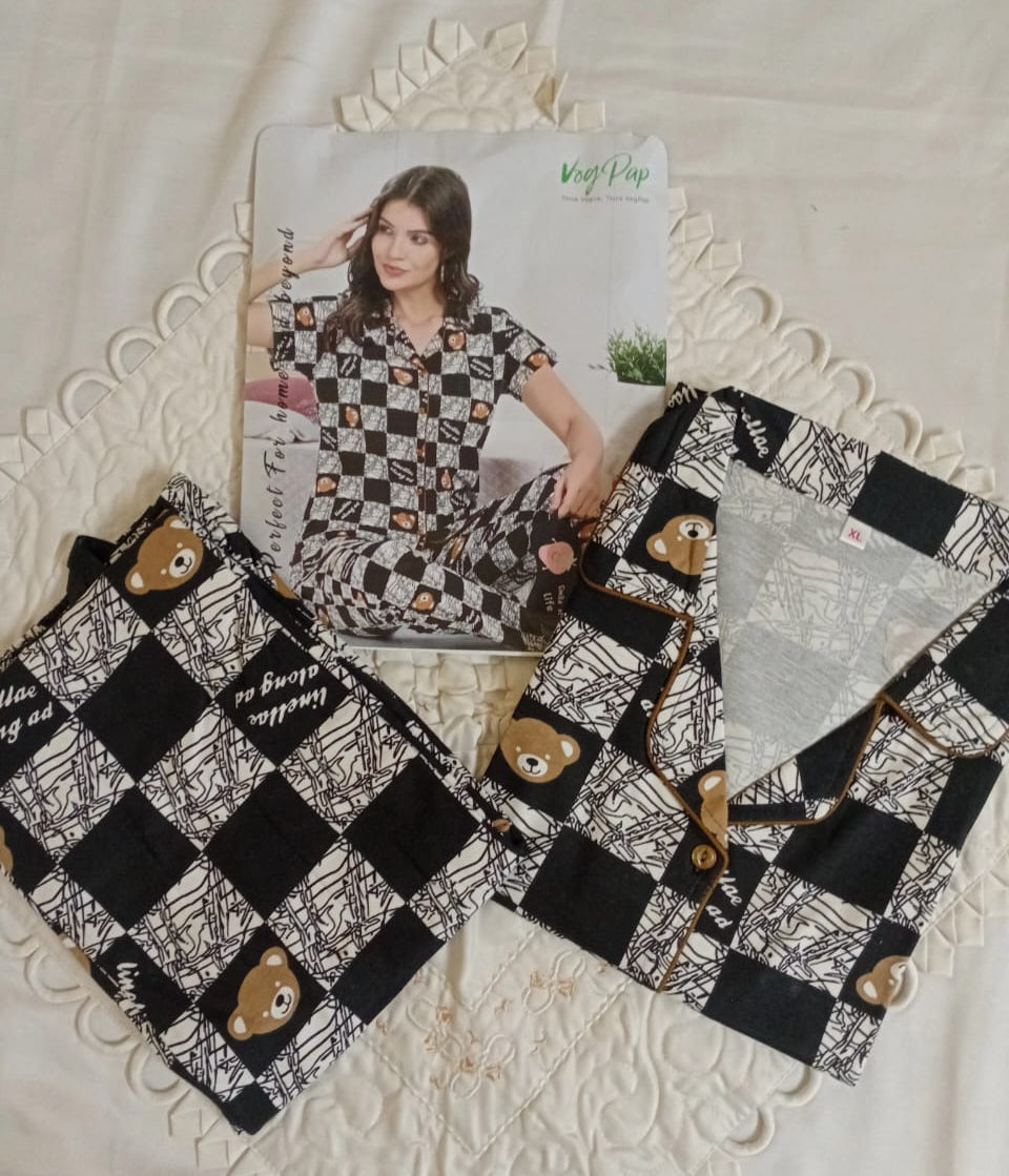 Woman wearing a black and white patterned nightwear set sitting on a couch.