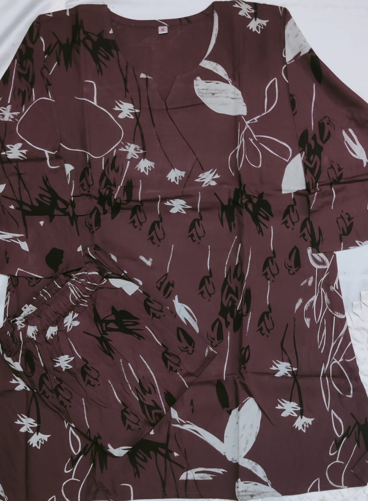 Floral patterned fabric with white and black designs on a brown background