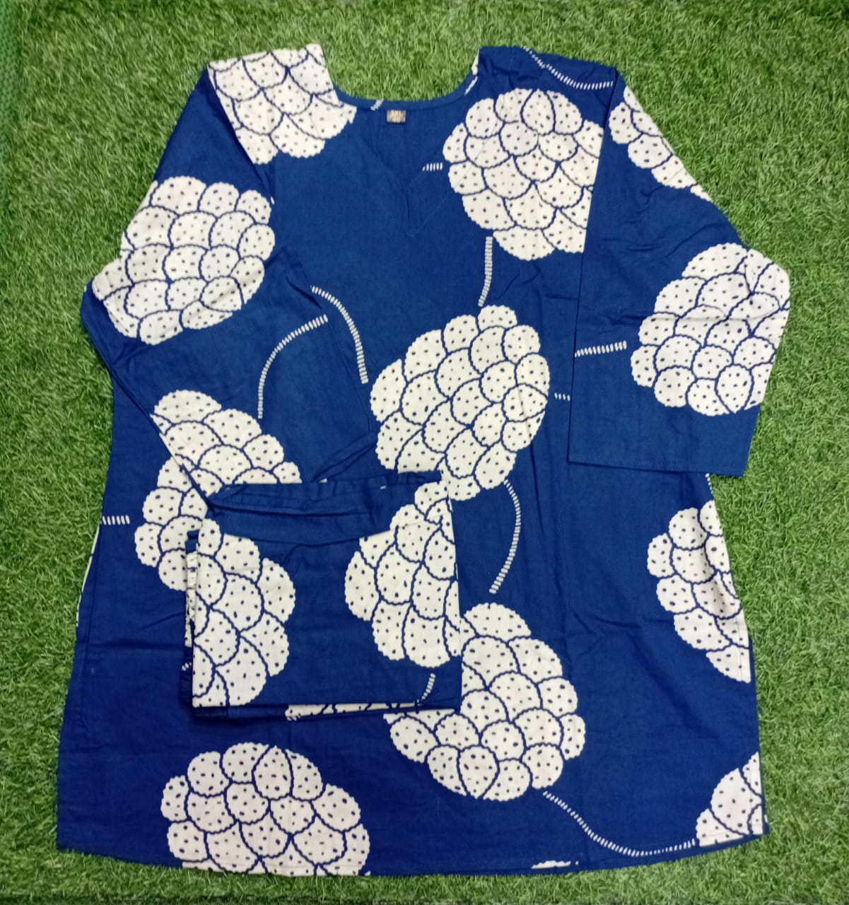 Blue dress with white floral pattern on a grass background
