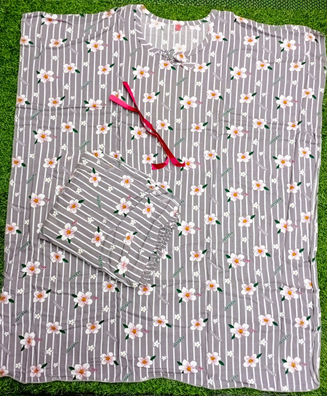 Floral-patterned shirt with a red ribbon on a grass background