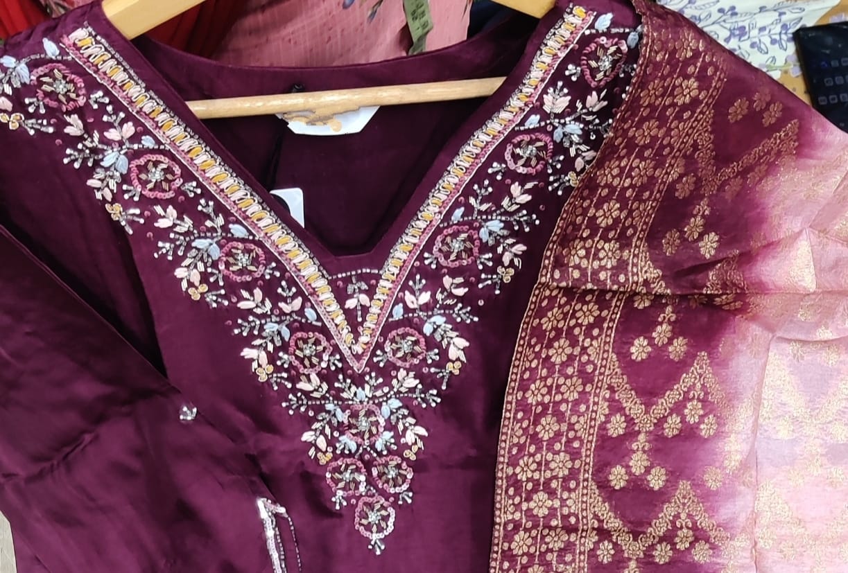 Maroon embroidered garment on a hanger with a blurred background