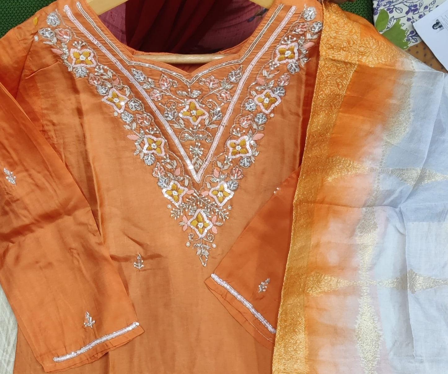 Orange embroidered kurta with a sheer white dupatta on a wooden surface