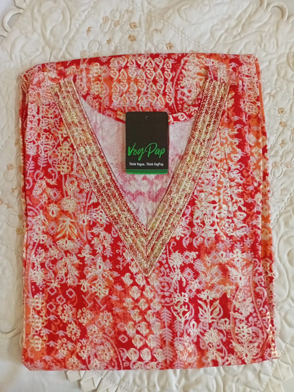 Red and white embroidered garment with a brand tag on a textured surface