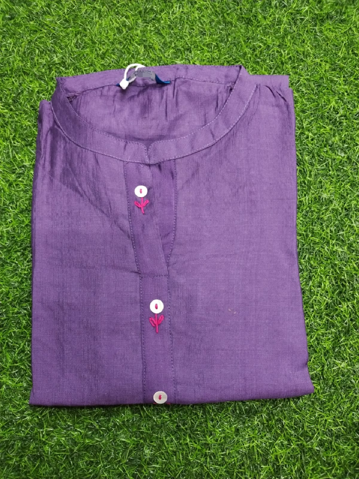 Folded purple shirt on a green grass background