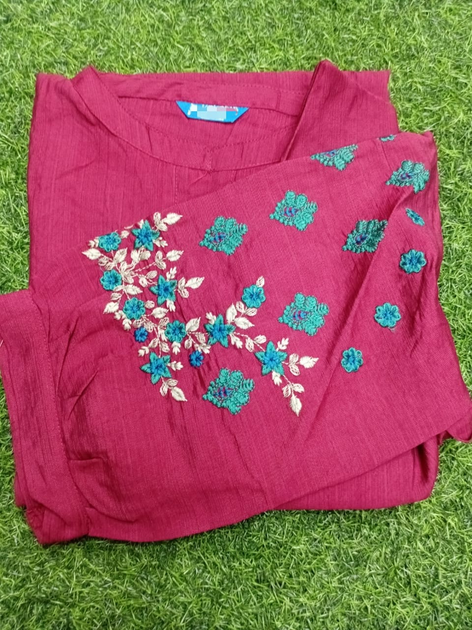 Pink fabric with floral embroidery on a grass background