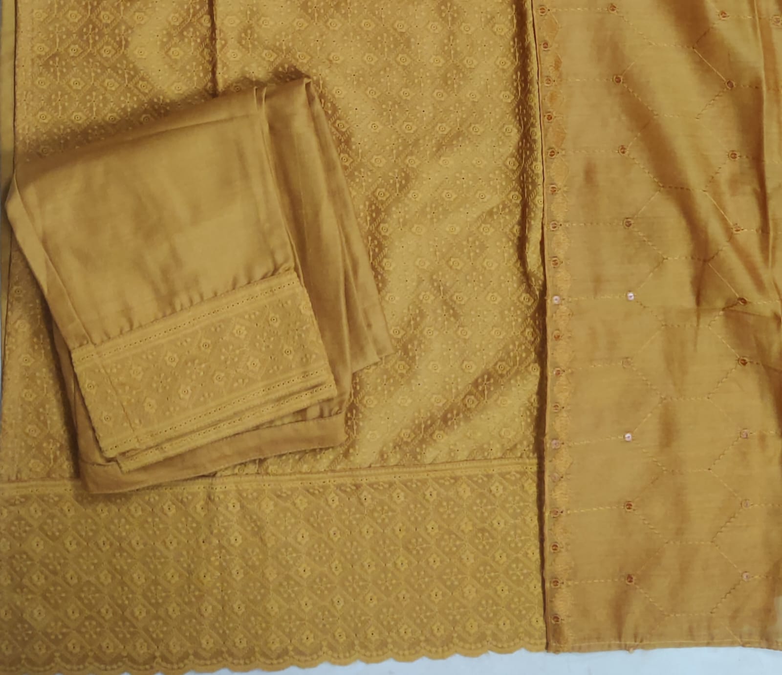 Gold fabric with intricate patterns and a folded piece of fabric on a matching background