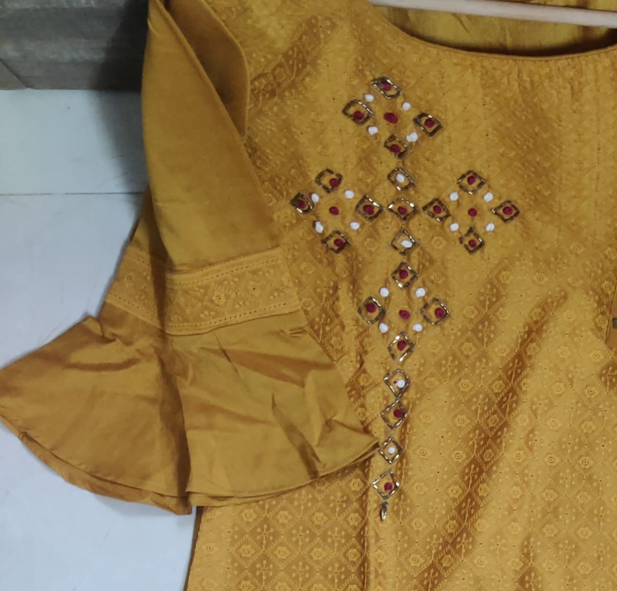 Yellow traditional outfit with intricate embroidery on a plain background
