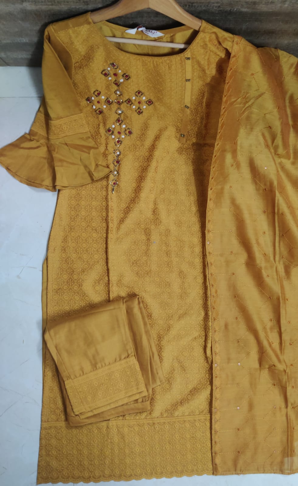 Mustard yellow dress with floral embroidery on a white surface