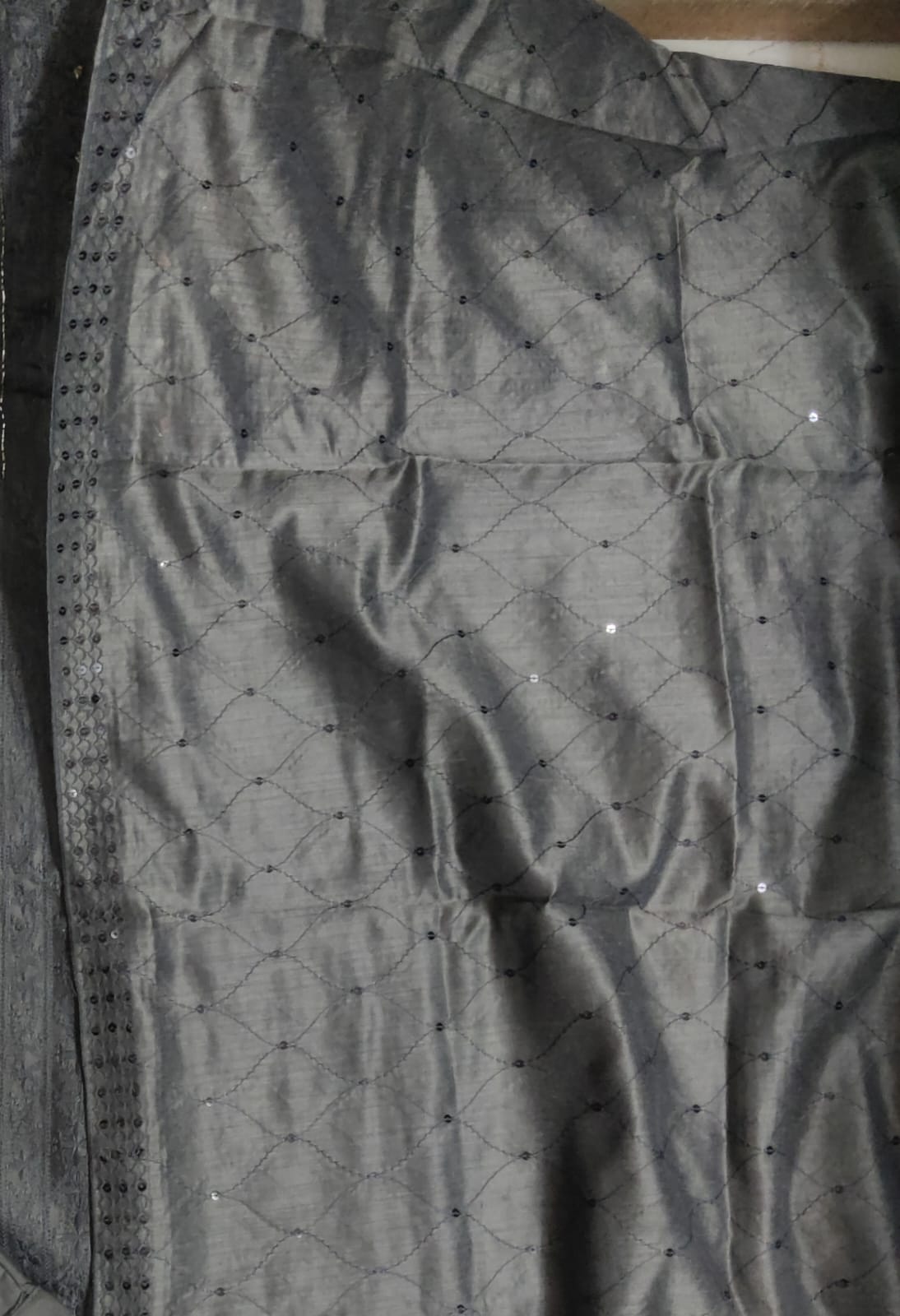 Dark gray fabric with a subtle pattern on a plain background