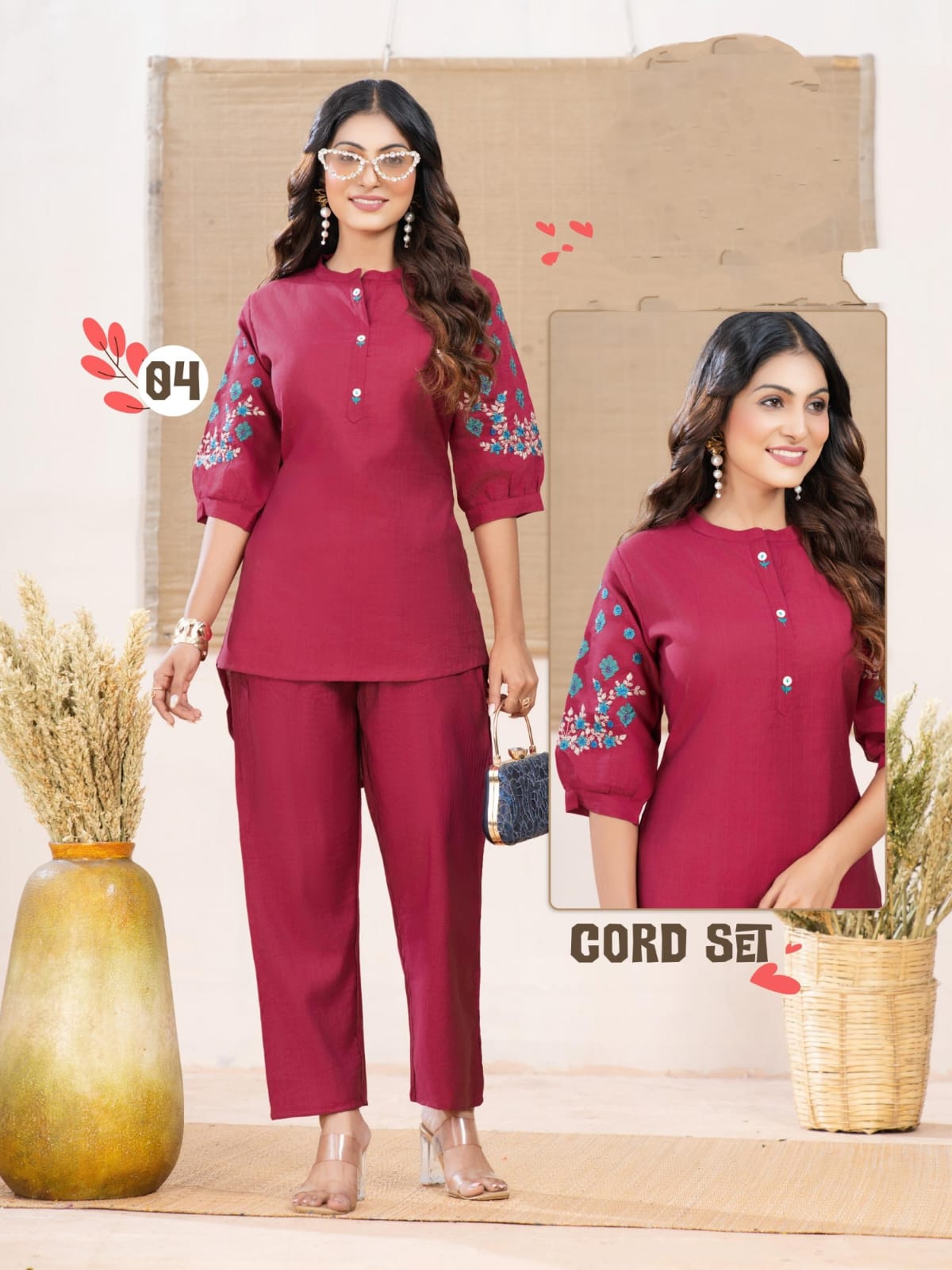 Woman wearing a maroon outfit with floral embroidery, standing against a neutral background.