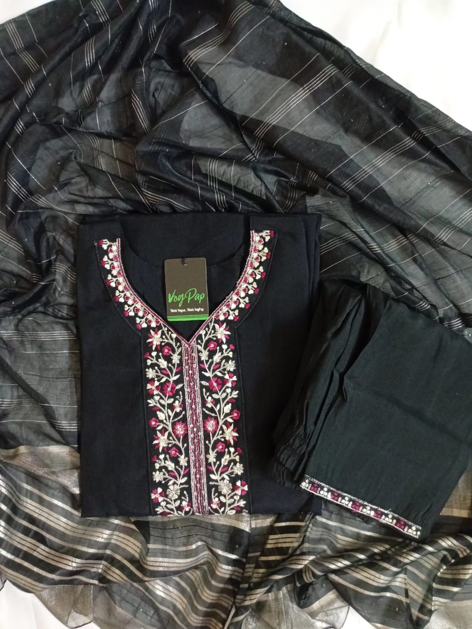 Black embroidered outfit on a checkered fabric background