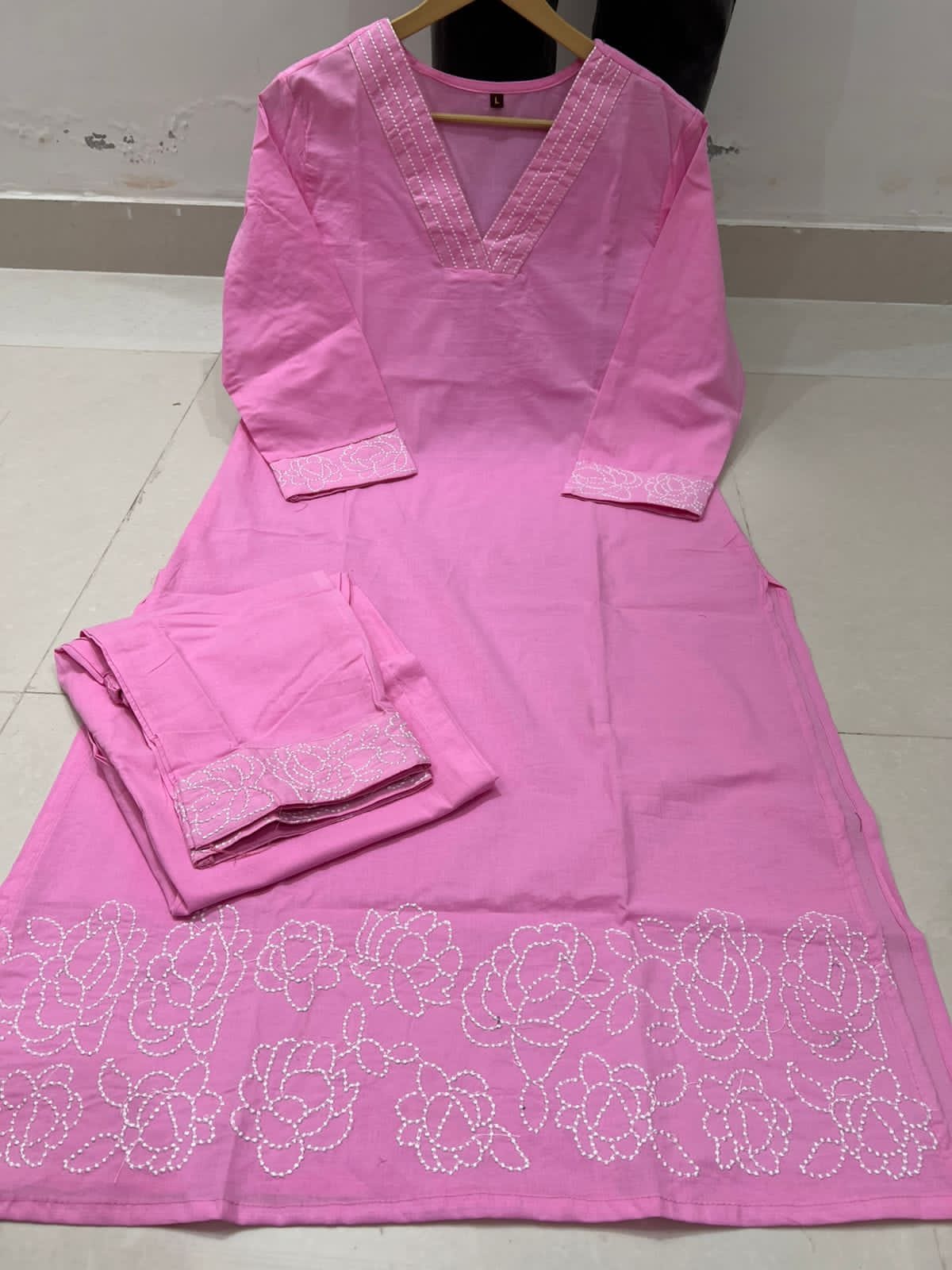 Pink kurta with white floral embroidery on a white floor