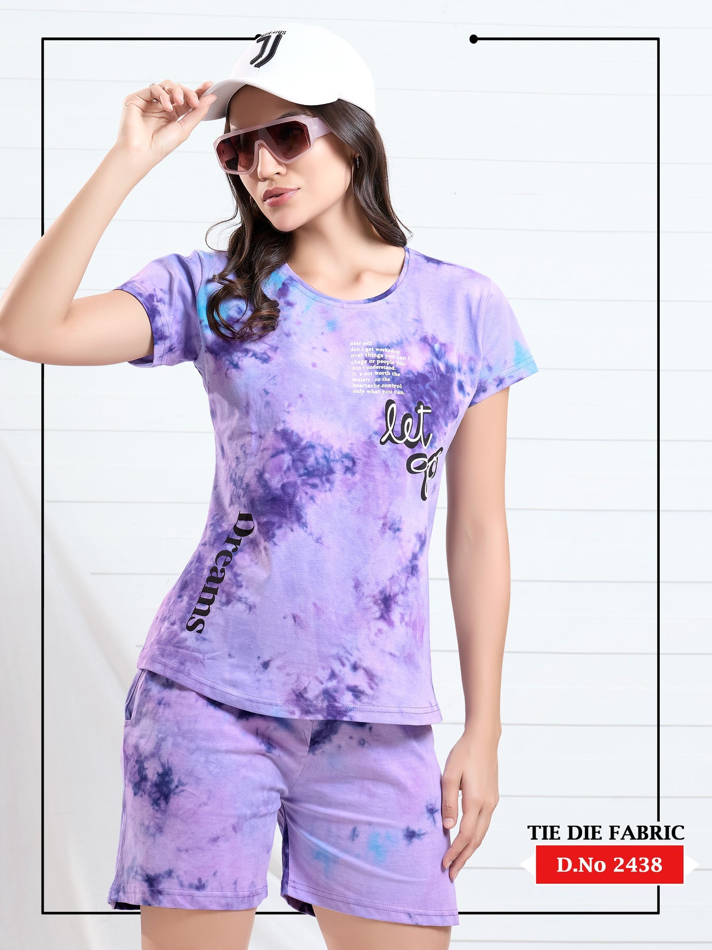 Woman wearing a tie-dye outfit with a matching top and shorts, holding a cap.