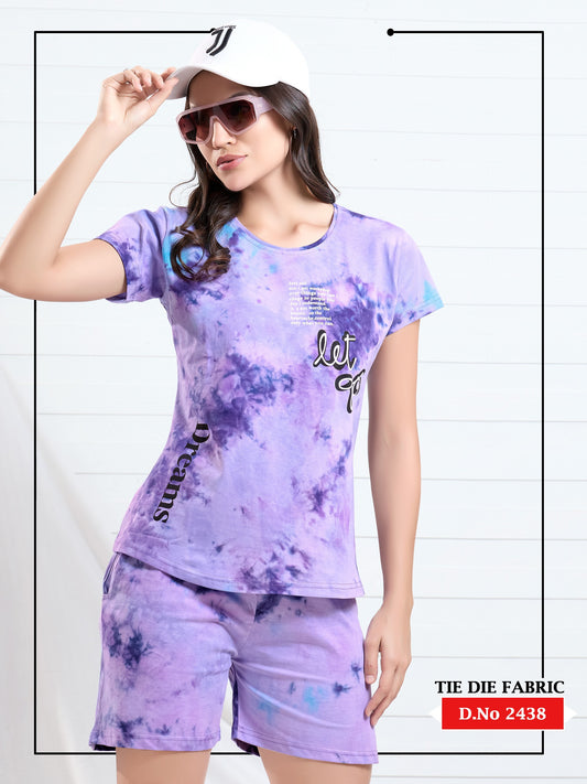 Woman wearing a tie-dye outfit with a matching top and shorts, holding a cap.