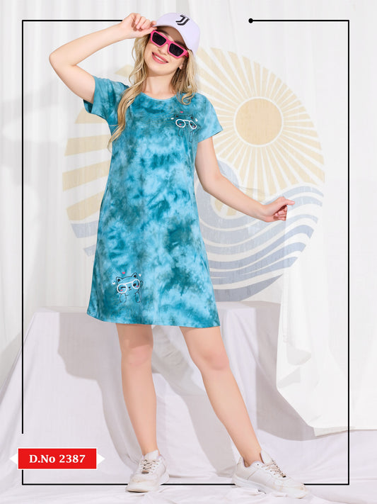 Woman wearing a blue tie-dye dress with sunglasses against a decorative background