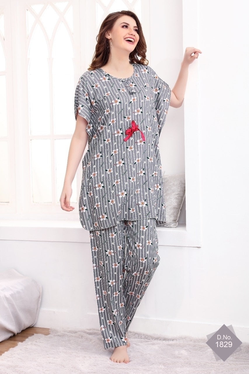 A woman standing in a room wearing a grey and multicolored flower print rayon kaftan pyjama set with a drawstring waist.