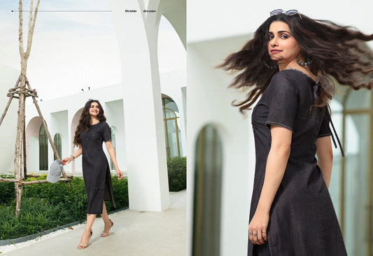 A woman wearing a black denim cotton straight cut kurti with front buttons, paired with white sandals, standing against an outdoor backdrop.