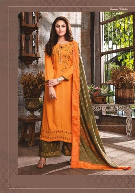 Woman in an orange and green traditional outfit standing in a decorative indoor setting.