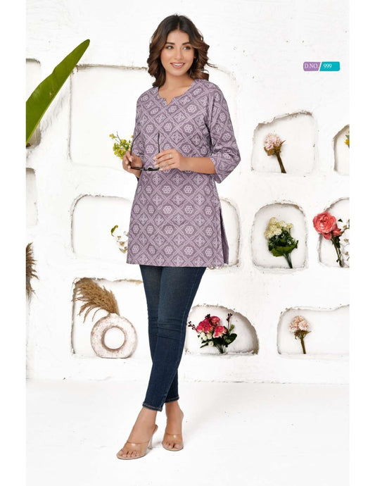 Woman wearing a patterned purple shirt and blue jeans against a decorative background with flowers and plants.