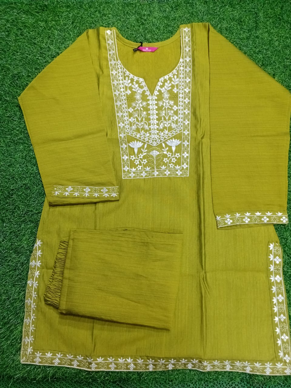 Green traditional outfit with white embroidery on a green background