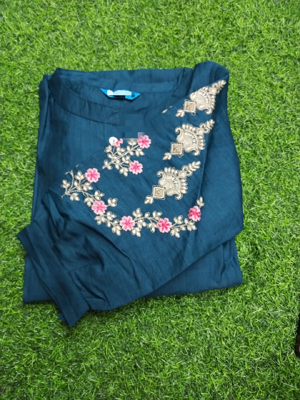 Blue garment with floral embroidery on a green grass background