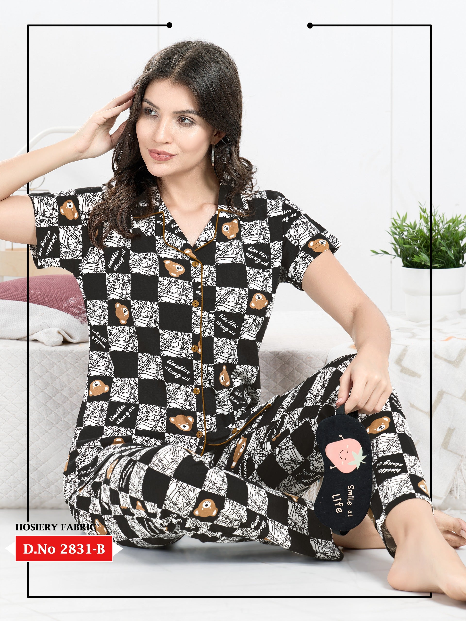 Woman wearing a black and white patterned nightwear set sitting on a couch.