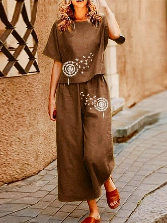 Woman wearing a brown outfit with dandelion designs on a stone pavement.