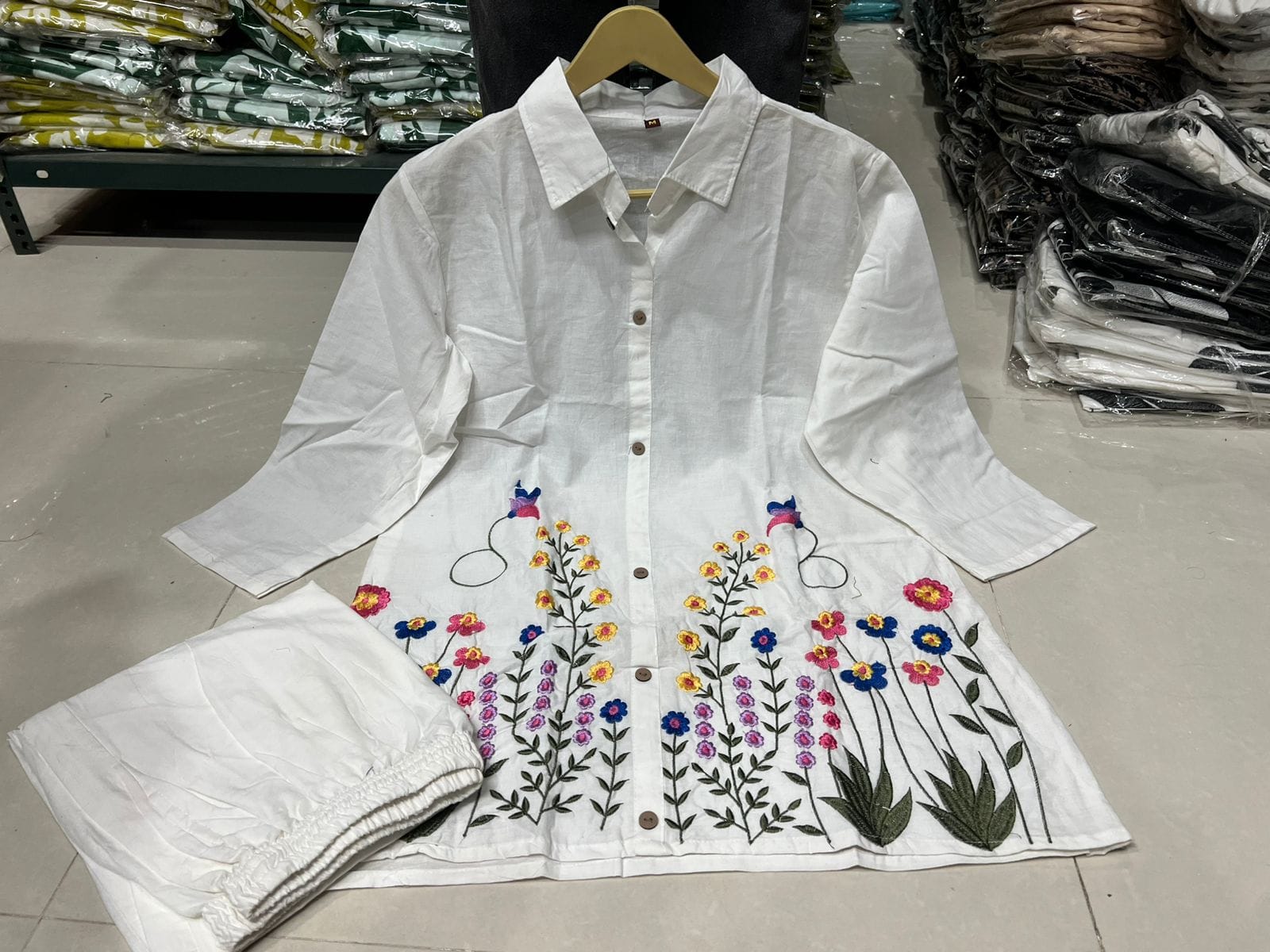White shirt with floral embroidery on a hanger in a store setting