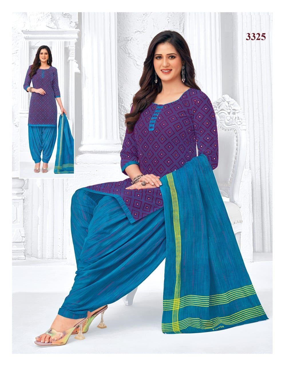 Woman wearing a purple top and blue patiala suit with green accents, standing in a white room.