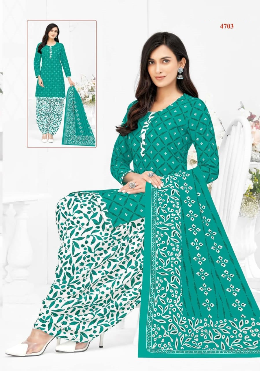 Woman wearing a green and white patterned outfit with a matching saree, sitting on a white chair.
