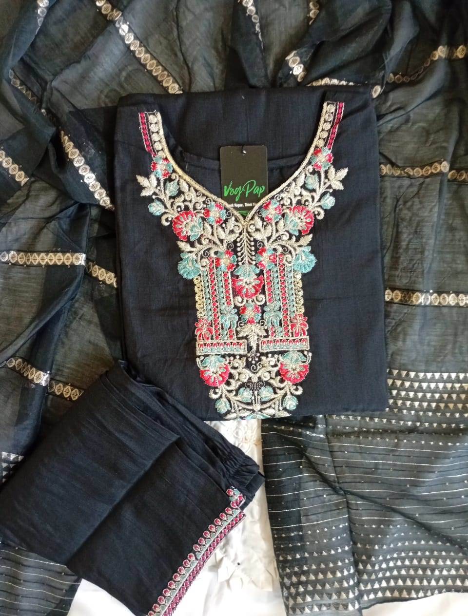 Black embroidered garment with a visible brand tag on a textured surface