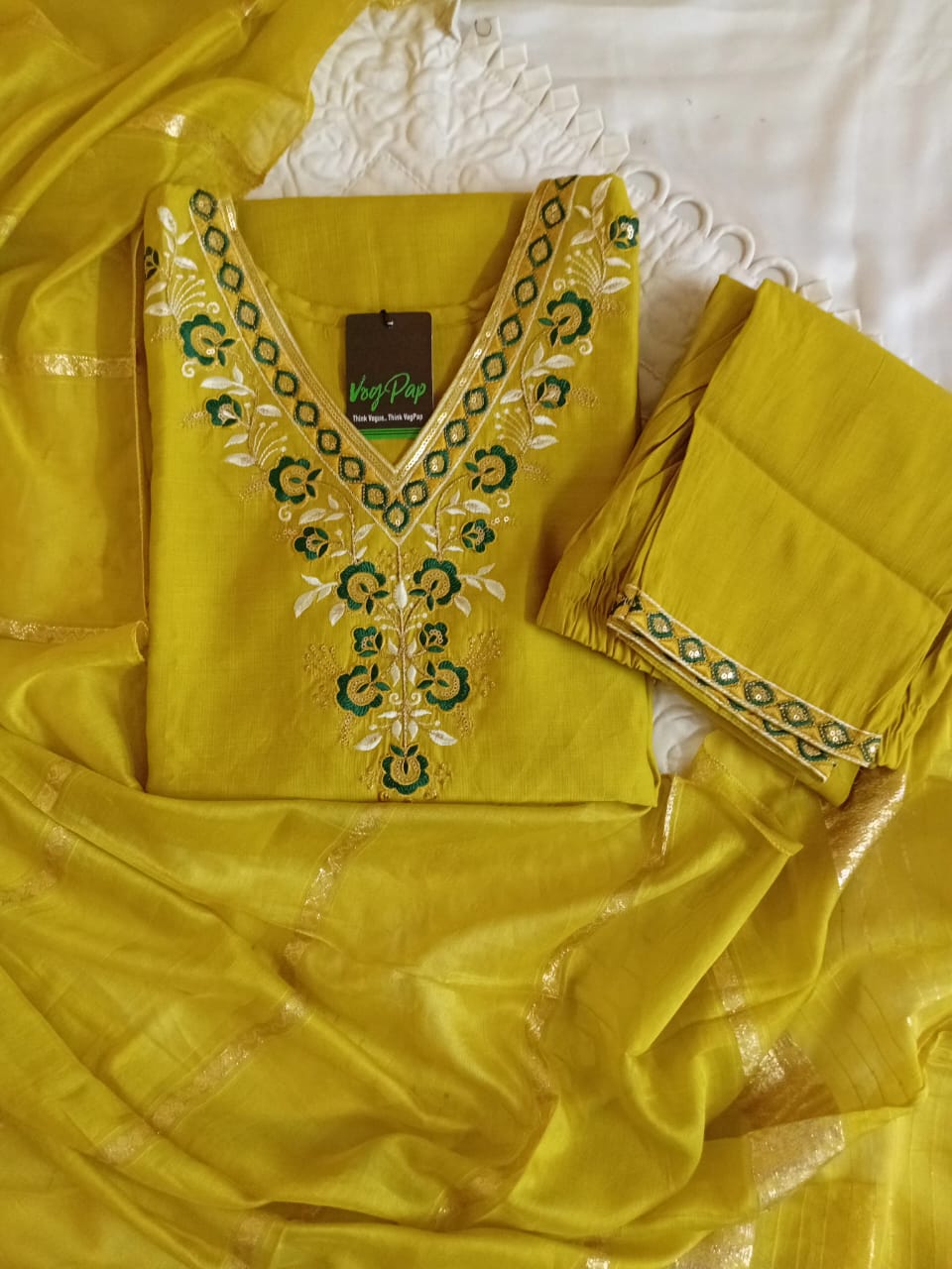 Yellow embroidered outfit with a brand label on a white background