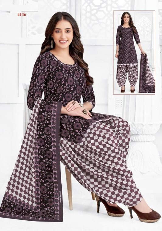 A woman wearing a floral print cotton fully stitched suit, consisting of a top and bottom with a dupatta.